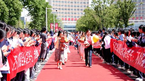 高三教师手捧鲜花迎着光走红毯